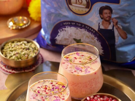 Rose Pistachio Kheer with pomegranate arils and dried rose petals served in glass cups on a gold tray, alongside Daawat Traditional Basmati Rice